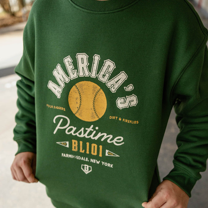 Close up of child wearing a forest green America's Pastime crewneck sweatshirt
