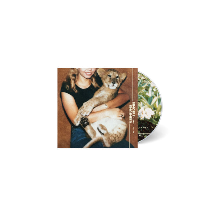 A CD by Sincere Engineer with a cover of a smiling young woman in a black shirt holding a lion cub. The partially visible disc displays swirling, vividly colored hallucinogenic flowers and foliage.