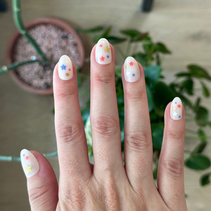 Star Spangled Party - Press-On | Short | Almond with milky neutral base and red, blue, and gold star press-on nails manicure