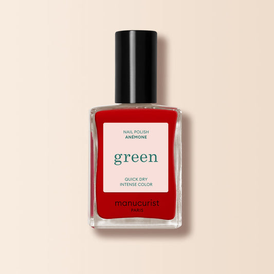 A bottle of Manucurist Anémone nail polish from the Green™ range, in a vibrant red shade, housed in a rectangular clear glass bottle with a black cap and a white label displaying product details.