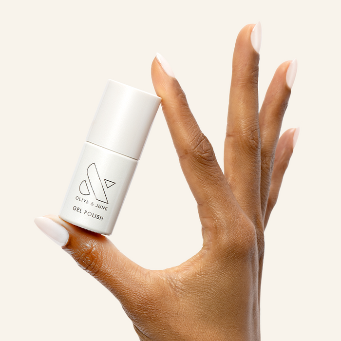 Atlas - Gel polish bottle held by hand with pearly white nails for a clean and elegant manicure by Olive and June