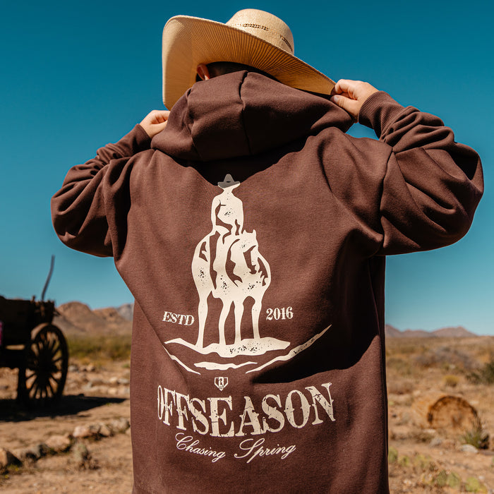 Person wearing a brown hoodie with a horse graphic and 'OFFSEASON' text in a desert setting