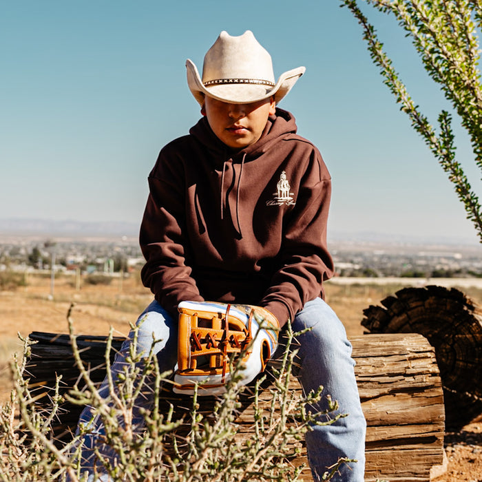 Person wearing a brown hoodie with a 'Chasing Spring' horse logo, sitting outdoors with desert landscape in the background