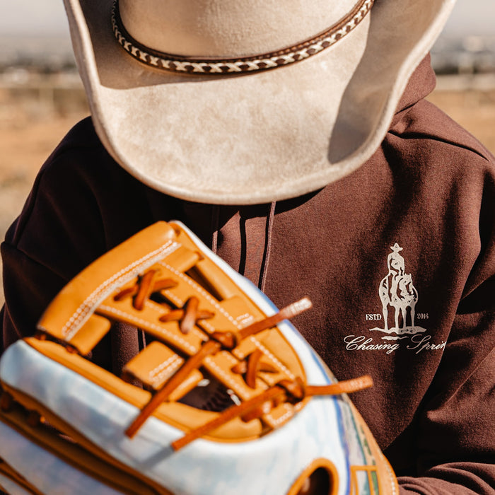 Person wearing a cowboy hat and brown hoodie with a horse 'Chasing Spring' logo.