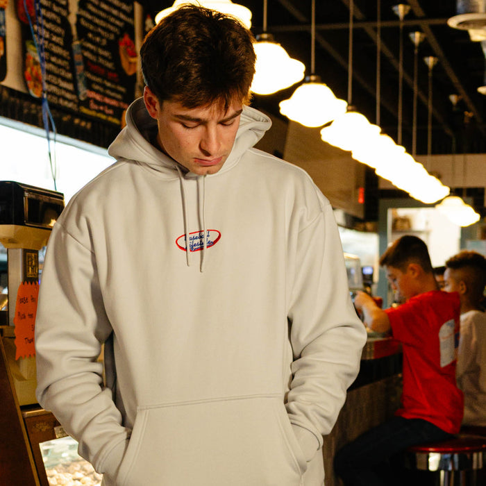 Person wearing a light gray hoodie with a 'Baseball Lifestyle' logo in an indoor setting