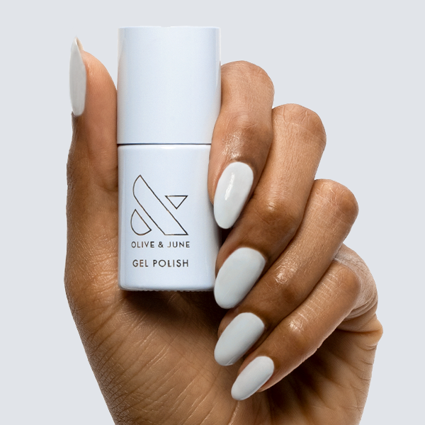 BP - Gel bottle held with nails painted in a soft icy light blue shade for a smooth, long-lasting gel manicure by Olive and June