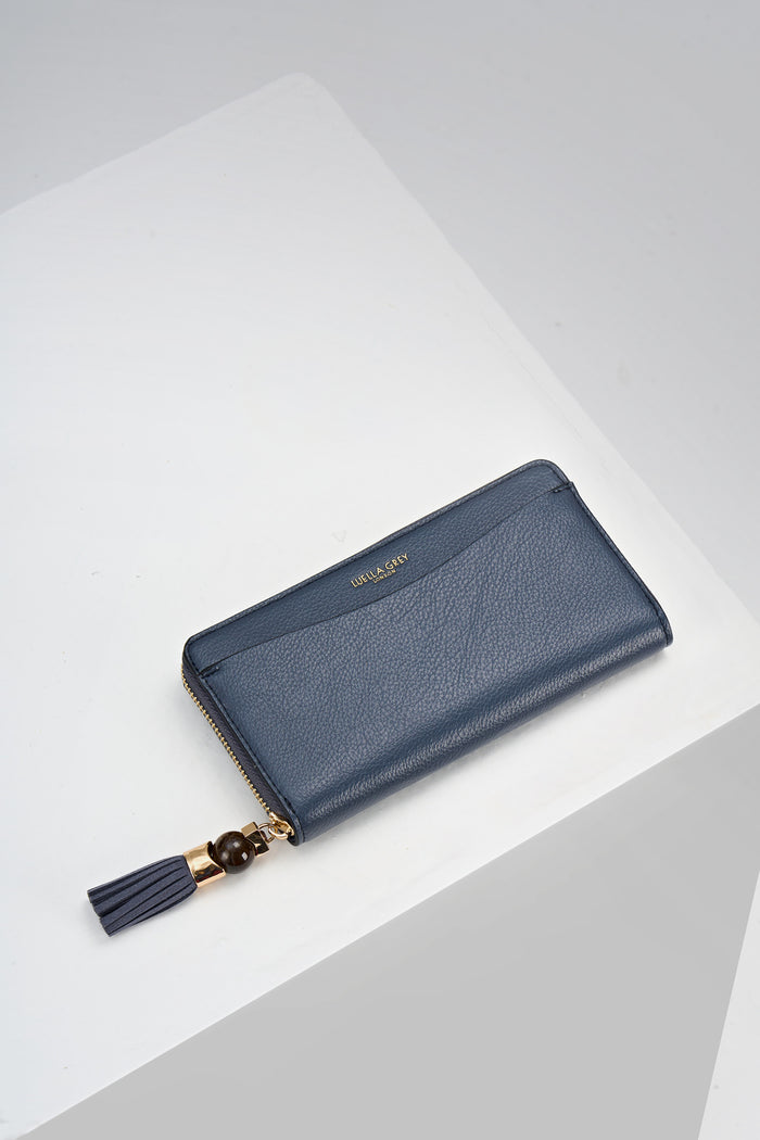 Overhead view of the front of Capriana Denim Blue faux leather Large Purse with mini Thames Tassel detail on the zip