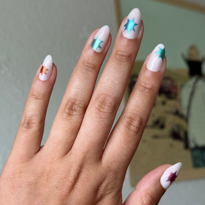 Chrome Burst - Press-On | Medium | Almond with white base and colorful chrome starburst accents on natural hand indoors