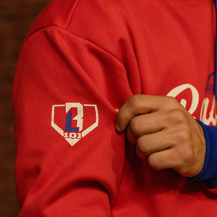 Close up of red Baseball Lifestyle hoodie sleeve showing BL101 home plate logo graphic and royal blue cuff