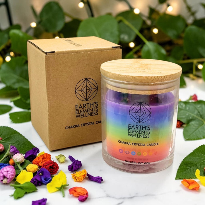 Earth's Elements Wellness candle with rainbow design and wooden lid, surrounded by flowers and leaves.