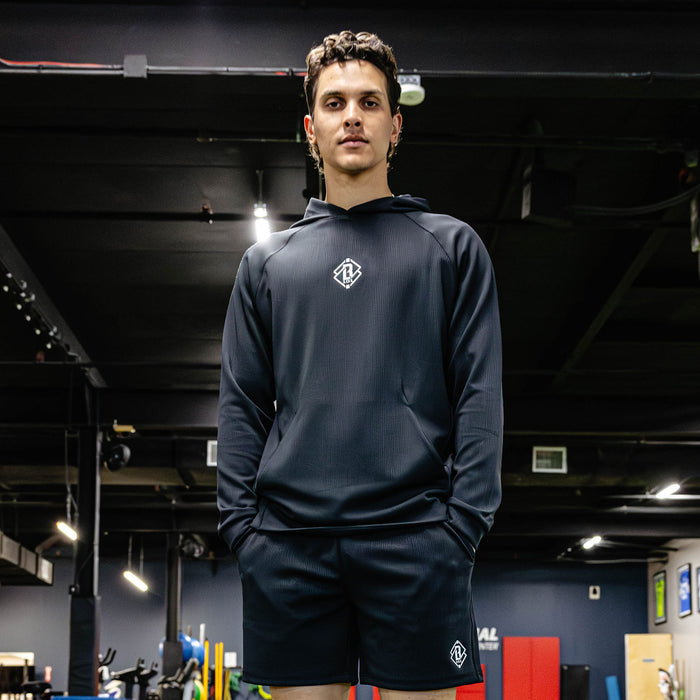 Person wearing a black athletic outfit with a logo in an indoor setting