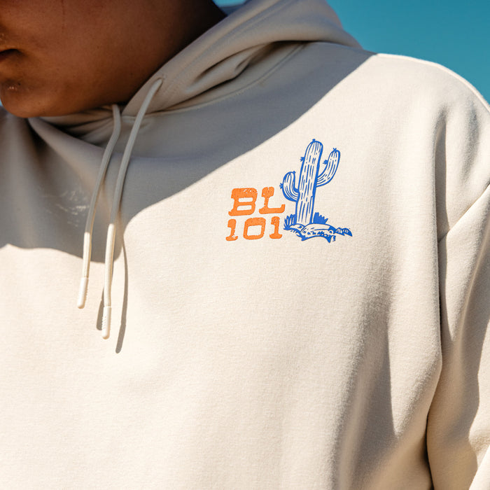Beige hoodie with a cactus design and 'BL 101' text on a clear blue sky background