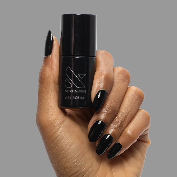 E+M - Gel polish bottle held by hand with glossy deep black nails for a sleek, long-lasting manicure by Olive and June