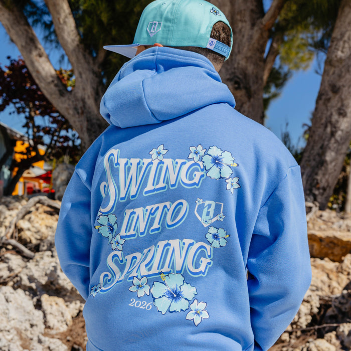 Person wearing a blue hoodie with 'Swing Into Spring' text and floral designs outdoors.