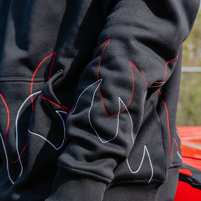 Close-up of layered red and white stitched flame outlines across the sleeve of a black hoodie