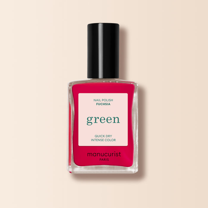 A bottle of Manucurist Fuchsia nail polish, featuring a black cap and vibrant pinky purple shade, from the Green™ range, shown on a light beige background.