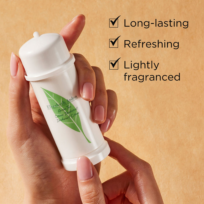 Hand holding Green Tea Cream Deodorant on a beige background. Green Tea Cream Deodorant is long-lasting, refreshing and lightly fragranced.