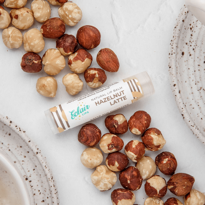 Hazelnut Latte lip balm with scattered hazelnuts
