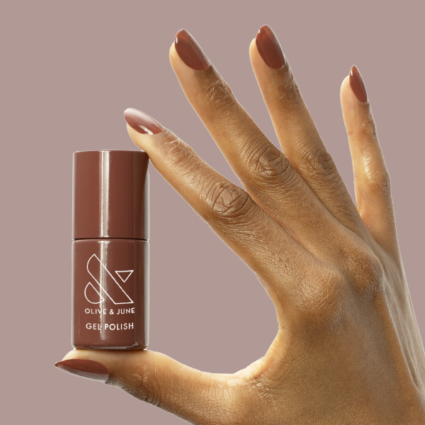 JJ - Gel bottle held by hand with nails painted in warm cinnamon brown for a cozy manicure by Olive and June