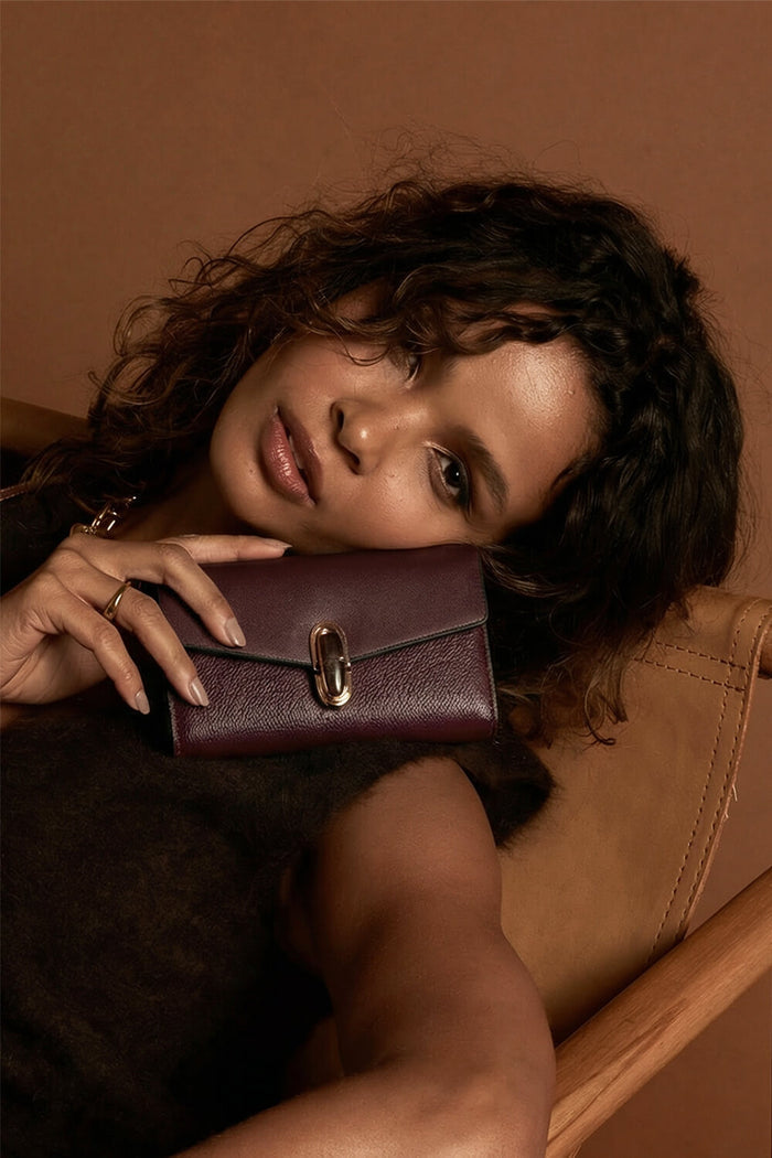 Female model holding Leontina Black Cherry Medium Purse in one hand