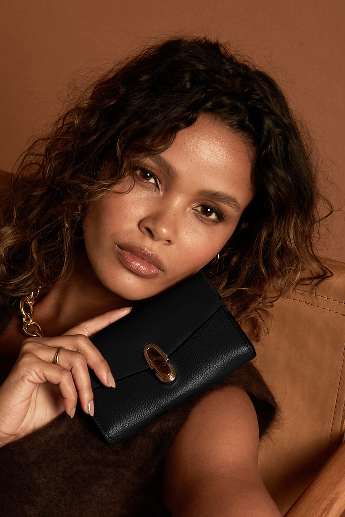 Female model holding Leontina Black Medium Purse in one hand