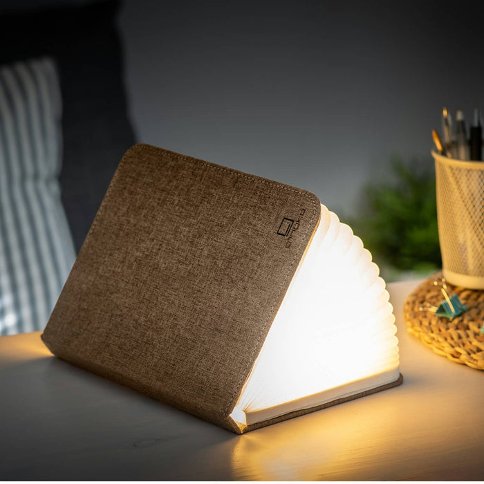 Gingko Design linen fabric smart book light with adjustable lamp arm and warm LED illumination for reading or relaxing.