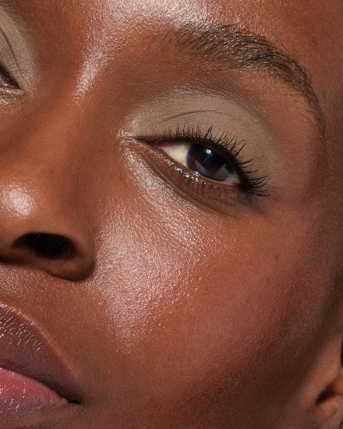 Extreme close up of a model wearing Mimi Liquid Silk Eyeshadow on a neutral background