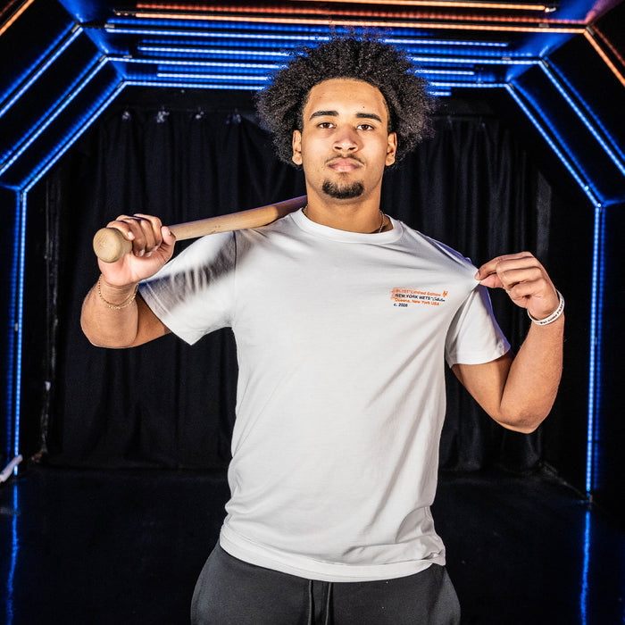 Adult model wearing white graphic tee with "New York Mets Drip" design
