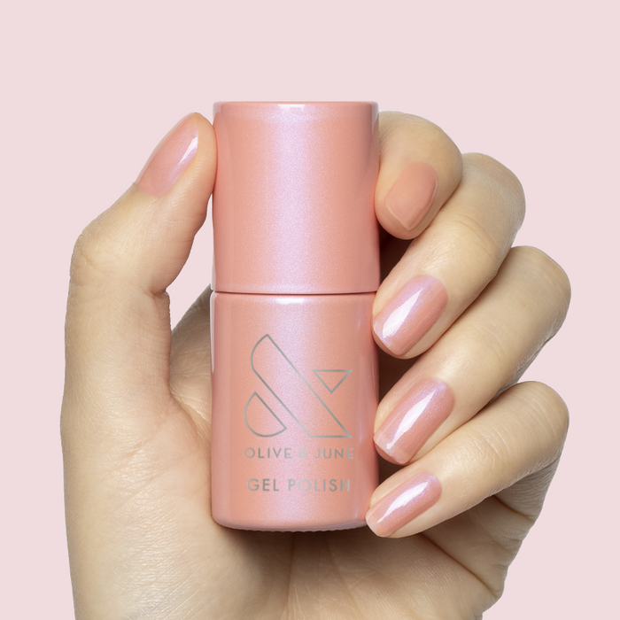 Hand holding Olive Y’all - Gel polish bottle with nails painted in sheer bubble gum pink-blue iridescent shade