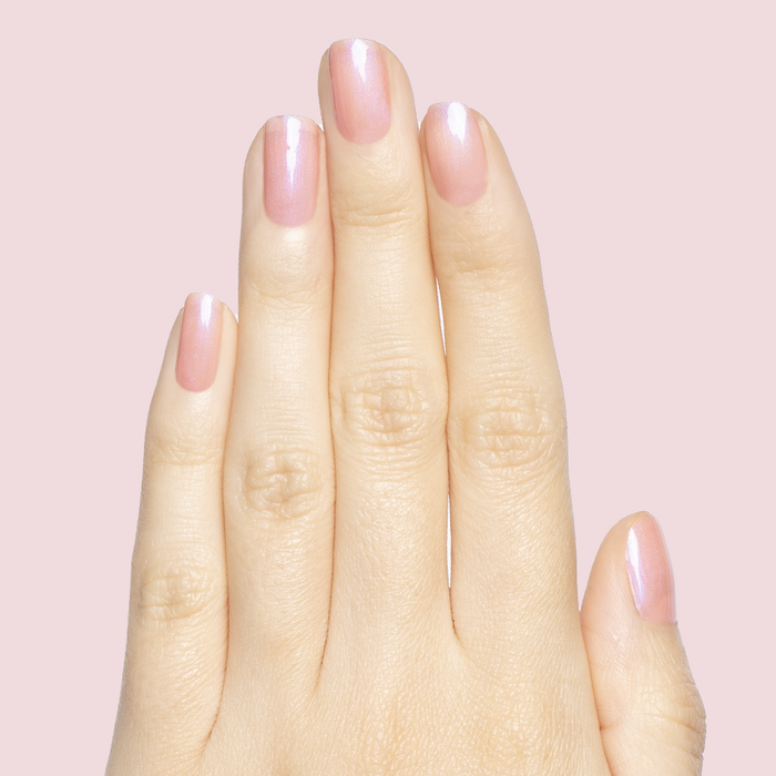 Hand with nails in sheer pink-blue iridescent shade using Olive Y’all - Gel for a delicate manicure look