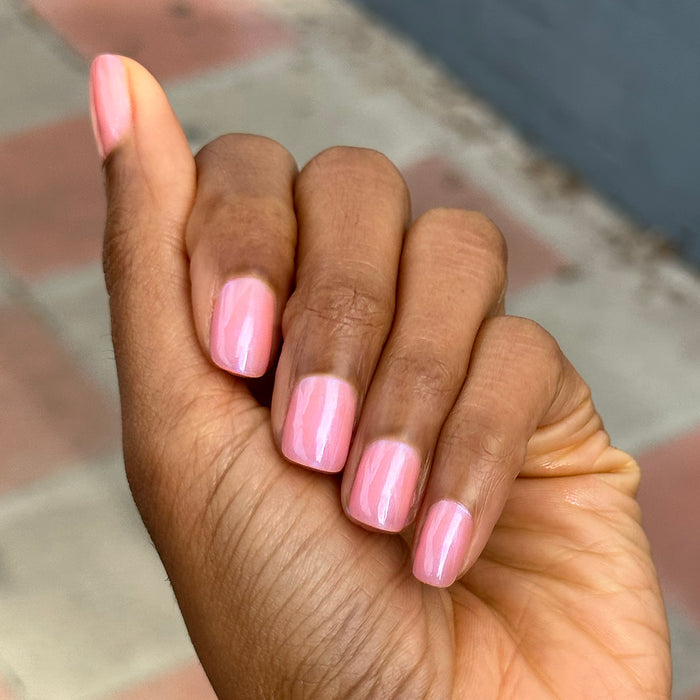 Hand with short nails polished in sheer bubble gum pink-blue iridescent shade using Olive Y’all - Gel polish