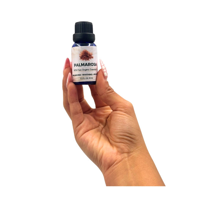 Hand holding a bottle of Palmarosa essential oil against a white background