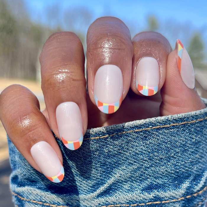 Parade French - Press-On | Medium | Oval with colorful multi-color checker print tips on natural nails in outdoor lighting