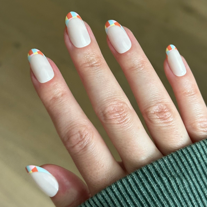 Parade French - Press-On | Medium | Oval with colorful multi-color checker print tips on natural hand for easy manicure