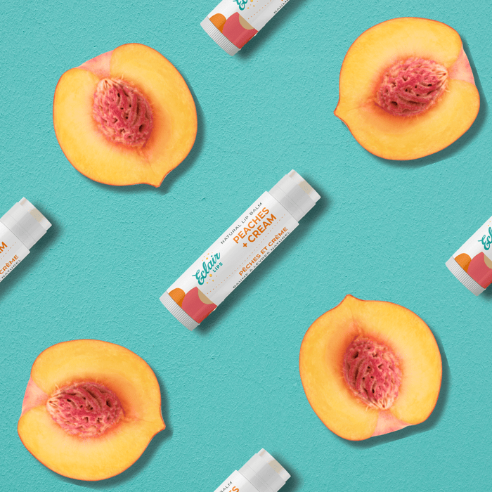 Flatlay of Peaches & Cream lip balm with fresh peach halves.