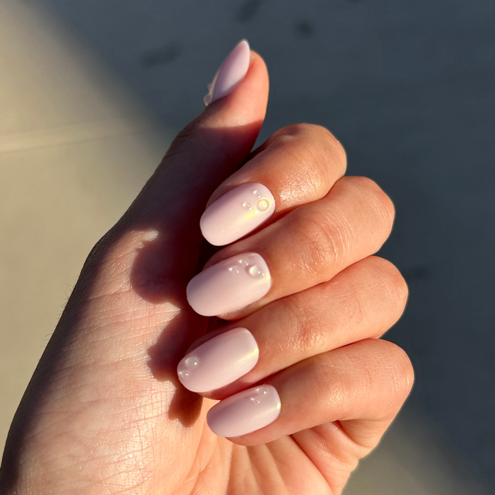 Pink Bubble Pearlescent - Press-On | Short | Round nails with soft pink iridescent polish and subtle bubble accents on natural hand