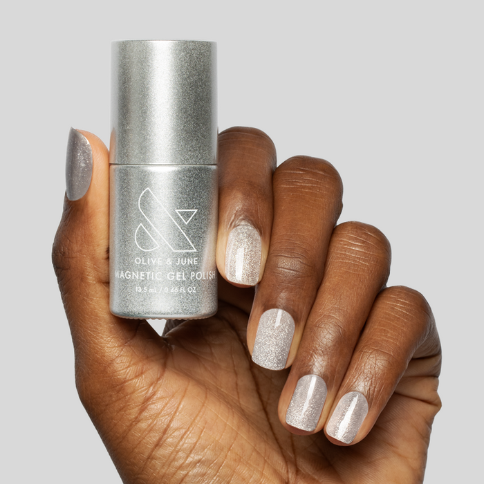 Hand holding Platinum Velvet - Gel bottle with nails painted in sheer silver shimmer magnetic gel polish finish