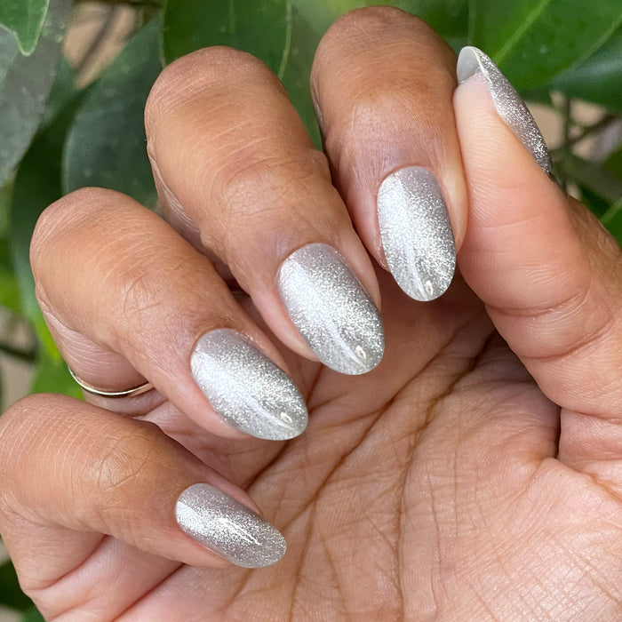Hand with nails painted in Platinum Velvet - Gel sheer silver shimmer magnetic polish showing soft sparkle effect