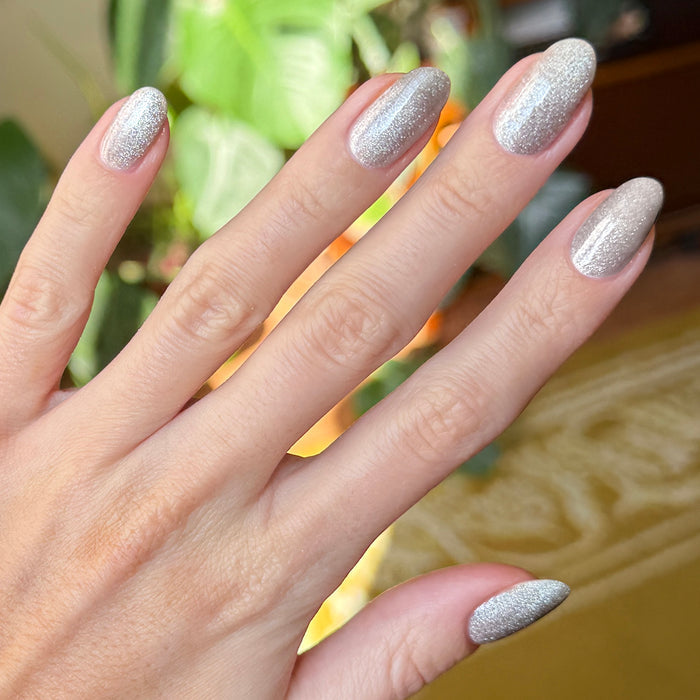 Hand with nails painted in Platinum Velvet - Gel sheer silver shimmer polish showing sparkling textured manicure finish