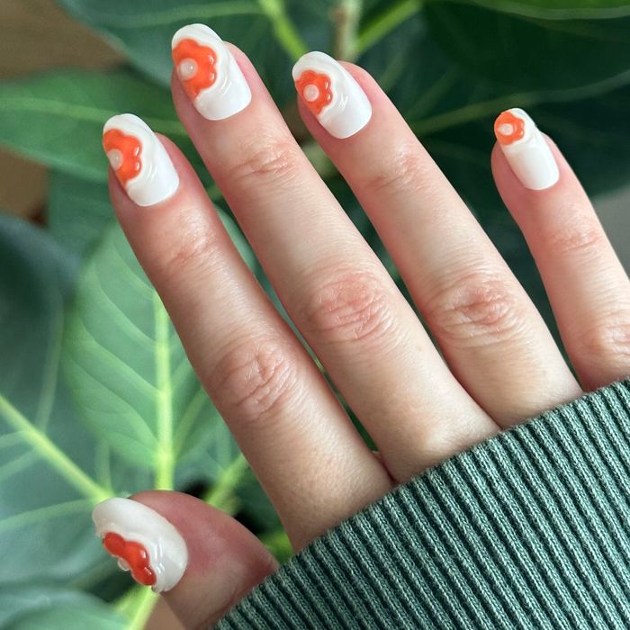 Puffy Bubble Flowers - Press-On | Short | Round white nails with raised orange floral details on hand over green leaves background