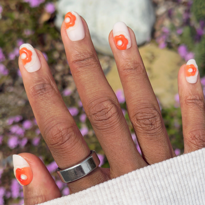 Puffy Bubble Flowers - Press-On | Short | Round neutral matte nails with raised orange floral accents on hand outdoors
