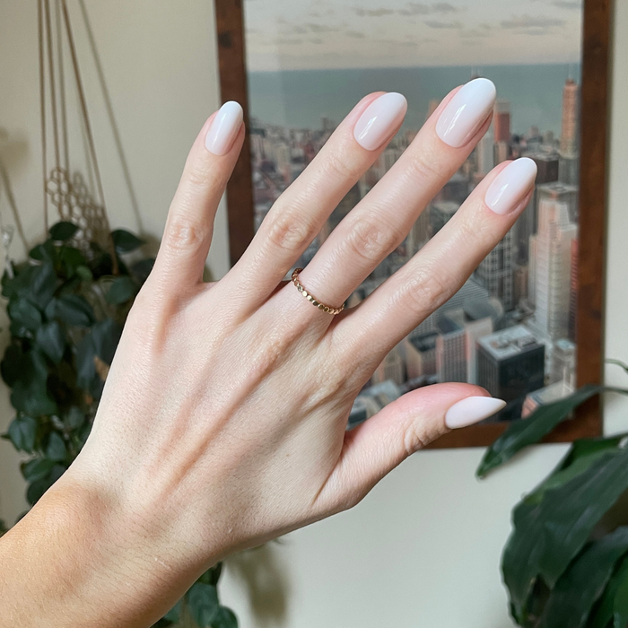 Pure White Syrup Gradient - Press-On | Medium | Oval showing hand with medium oval bright white gradient press-on manicure indoors