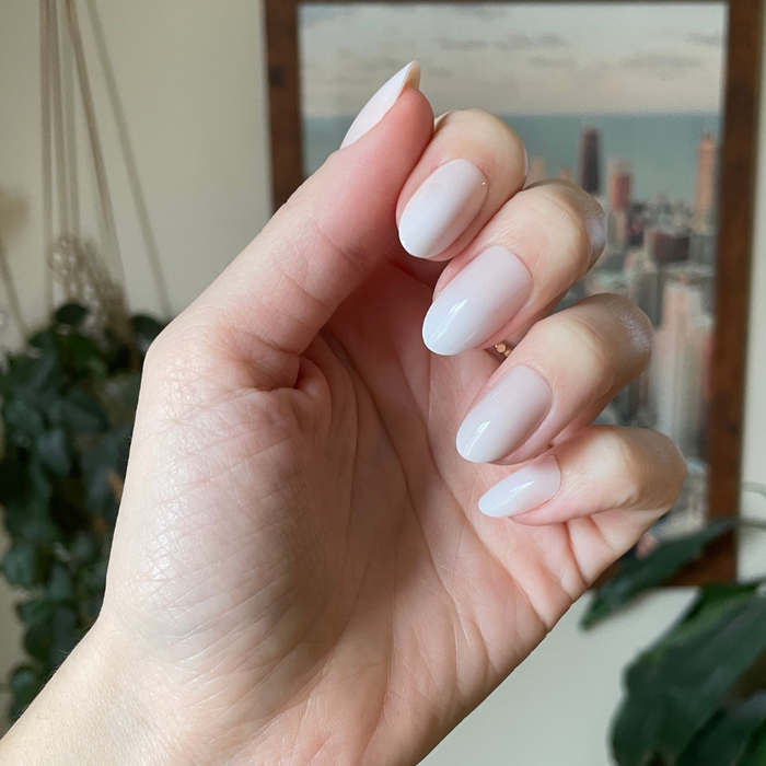Pure White Syrup Gradient - Press-On | Medium | Oval showing hand with medium oval white gradient press-on manicure indoors