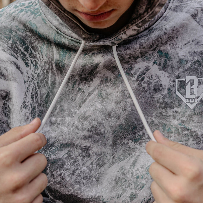 Person wearing a gray hoodie with a BL101 logo, holding the drawstrings