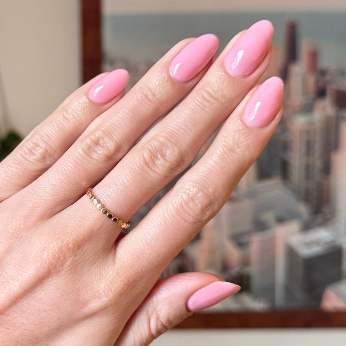 Hand with nails coated in a sheer pink Saltwater Taffy - Gel polish for a smooth, long-lasting at home manicure.