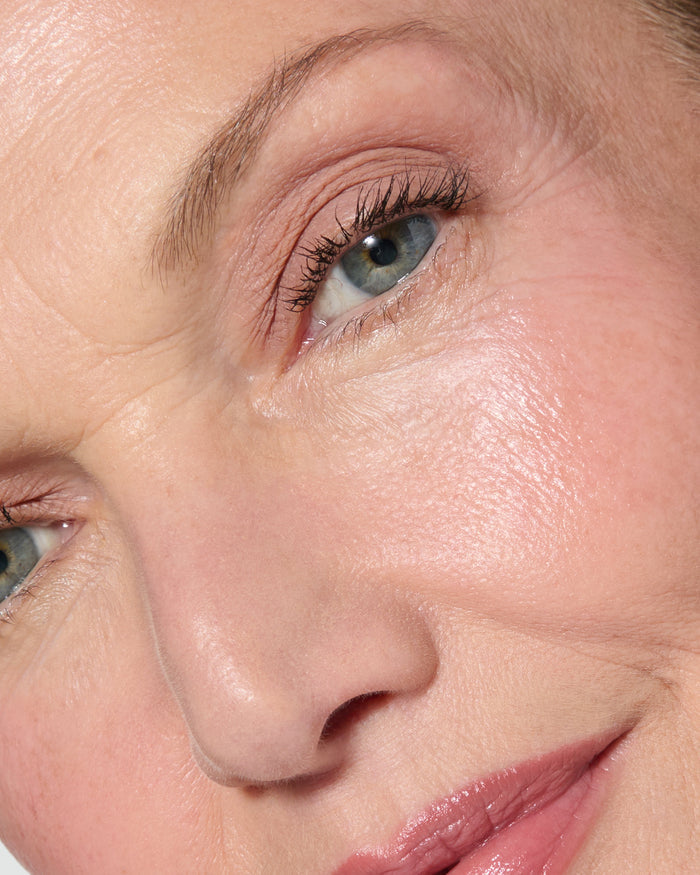 Extreme close up of a model wearing Silvia Liquid Silk Eyeshadow on a neutral background