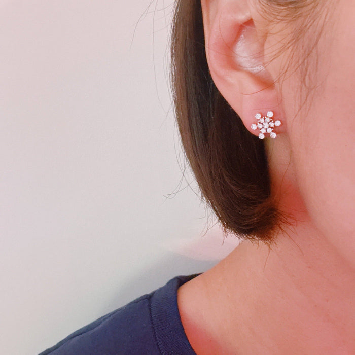 Ellison+Young snowflake stud earrings with intricate snowflake design in silver metal on a white background