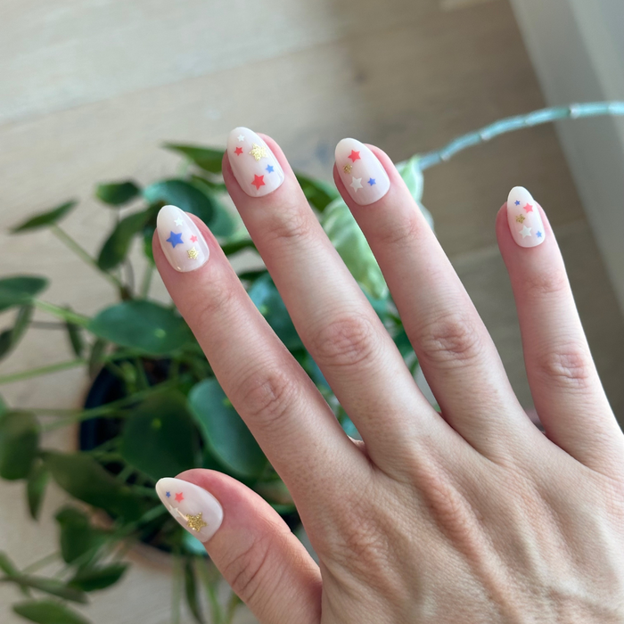 Star Spangled Party - Press-On | Short | Almond features festive red, blue, and gold star mani on milky base nails.