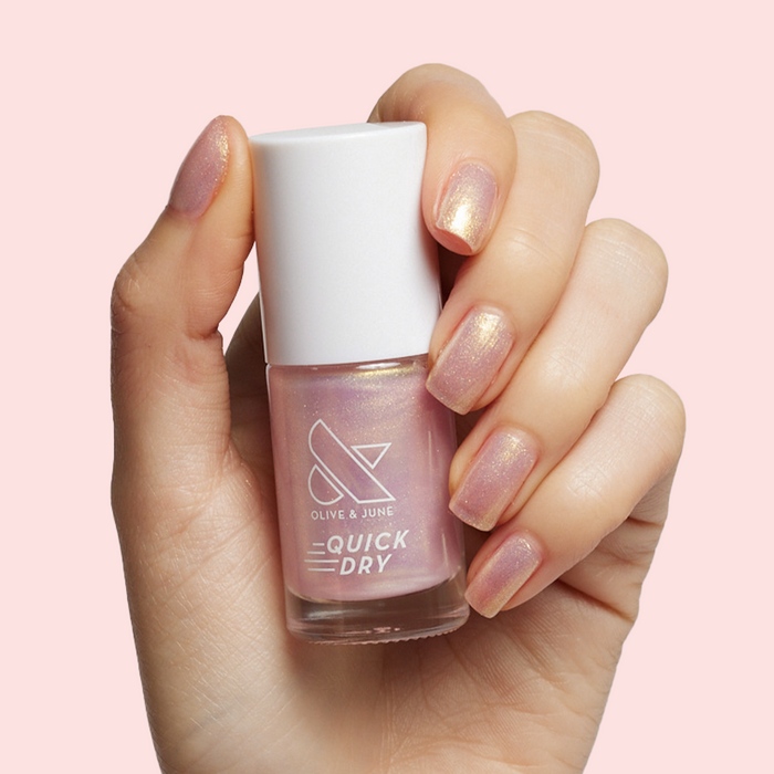 Hand with sheer pink iridescent Sugarcoat quick dry polish mani on natural skin against soft pink background