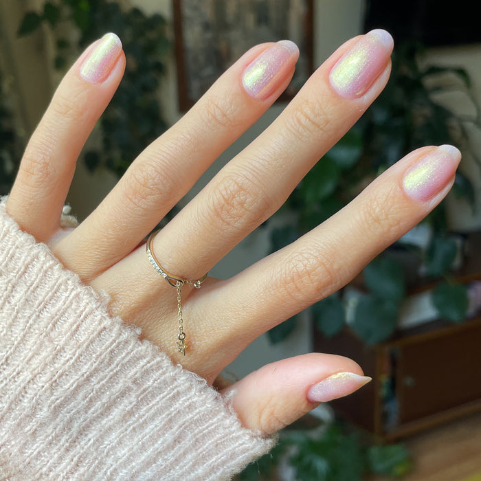 Hand with Sugarcoat sheer and shimmery pink iridescent quick dry polish manicure on natural nails in soft daylight